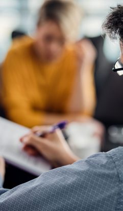 Back view of psychotherapist writing notes during a meeting with a couple.